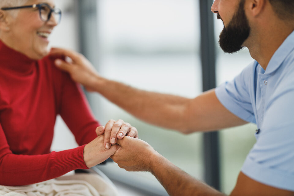 Soignante tenant les mains d’une patiente âgée